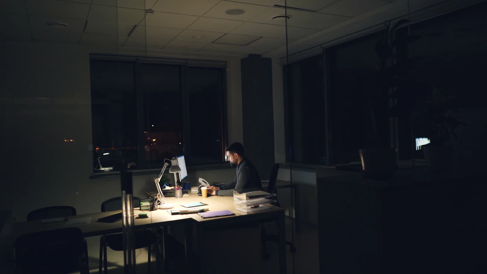 Iemand werkt laat aan een verlicht bureau — klantvragen buiten kantooruren
